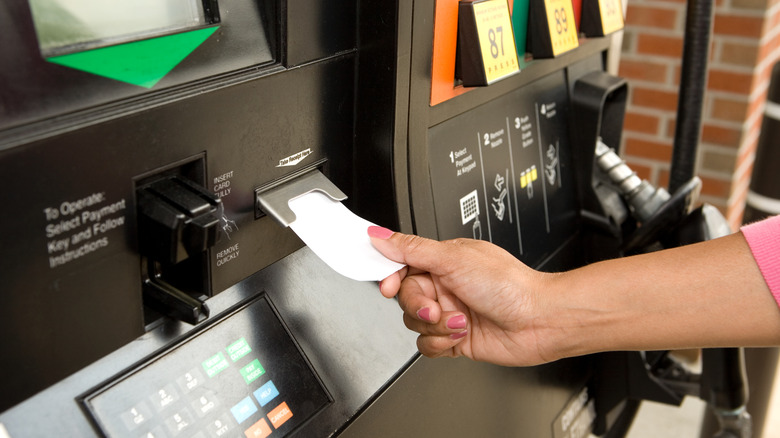 A woman's hand getting a receipt from a gas pump