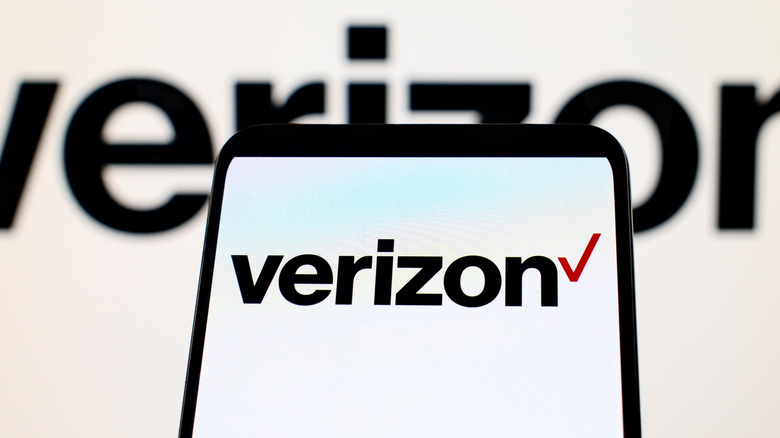 The Verizon logo displayed on a smartphone with a blurry Verizon background