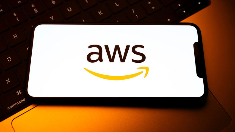 A smartphone placed on a laptop keyboard displays the logo of the AWS cloud computing service