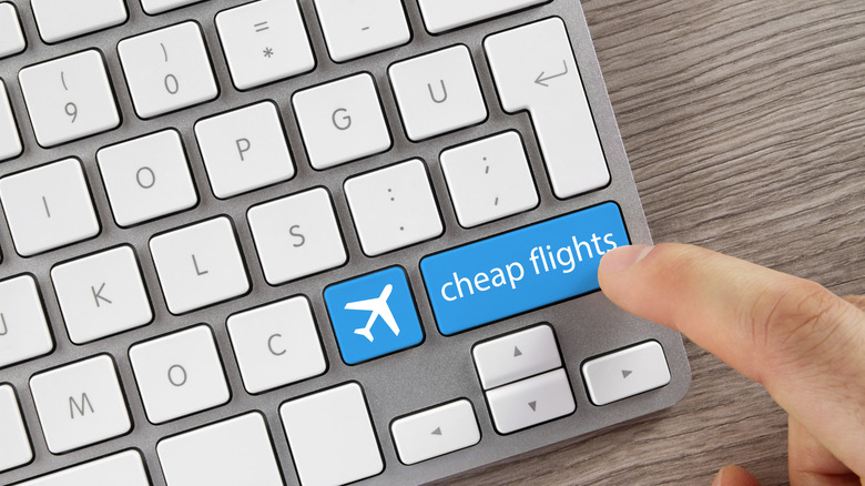 Person tapping keyboard with an airplane key and cheap flights key
