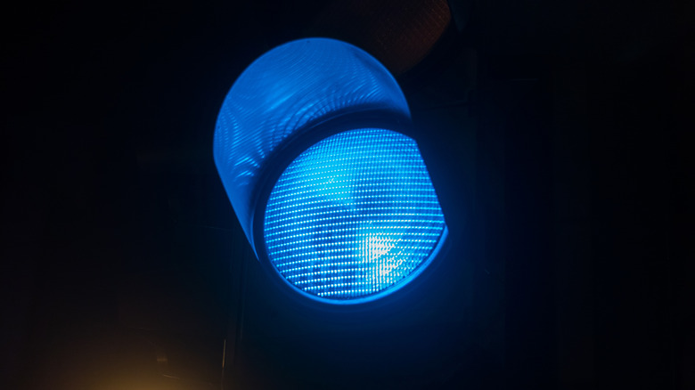A blue traffic light against a black background