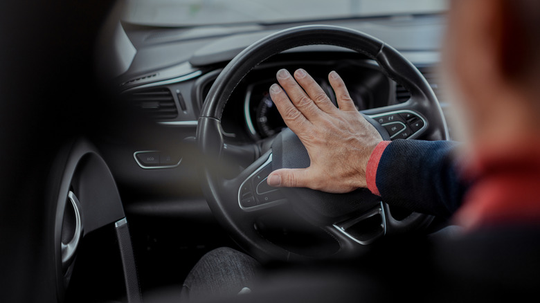 A driver pressing the horn in a modern Renault