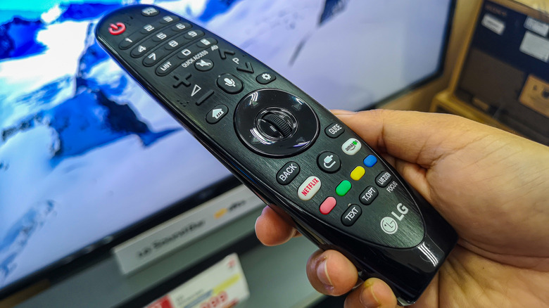Person holding LG TV remote with colored bottoms near the bottom