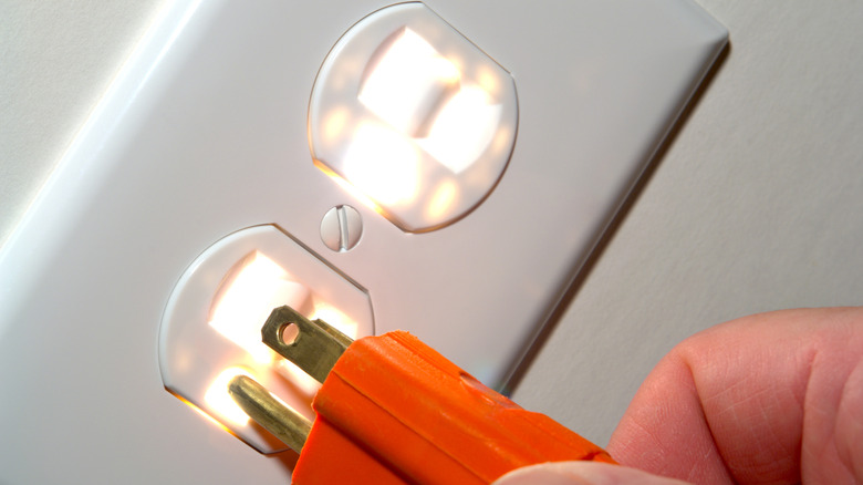 Fingers inserting a Type B prong in a North American electrical socket
