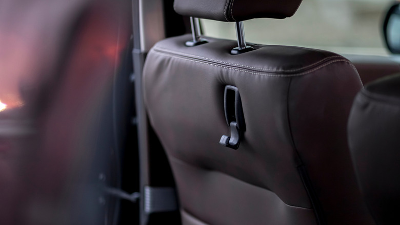 A factory hook on the back of a driver's seat upholstered in brown leather