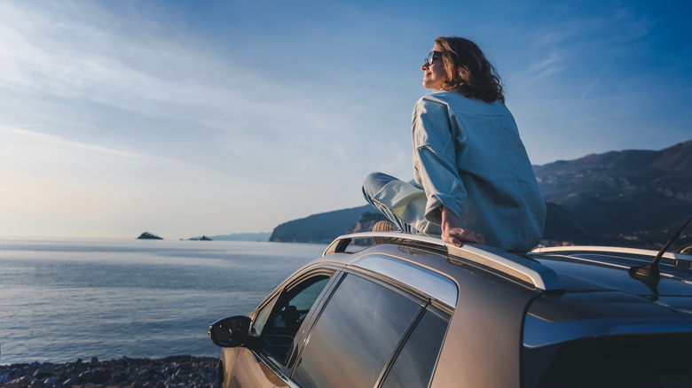 A person sitting on the roof of their car