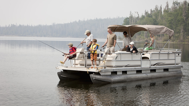 Adults and children fishing on a pontoon boat on a lake