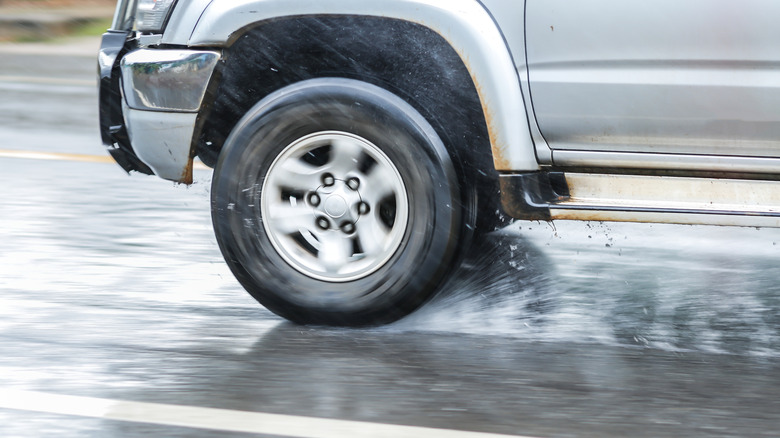 SUV driving on wet roads, close-up of the tire and wheel