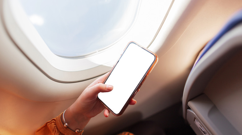 Person holding a mobile phone on a plane