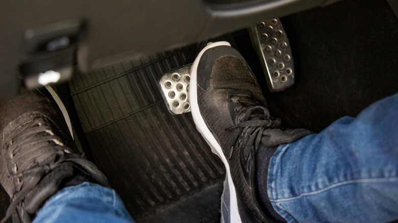 Pressing on the car's brake pedal with the right foot.