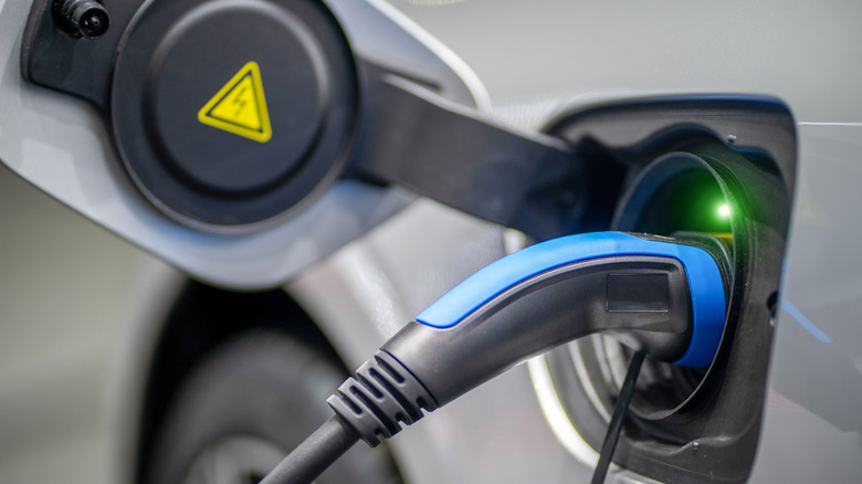 An EV parked at a service station with the power supply plugged in.