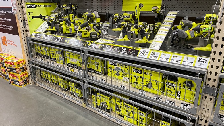 A shelf at Home Depot full of green Ryobi 18V One+ tools