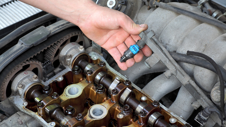 Car mechanic fixing fuel injector in a dual camshaft gasoline engine