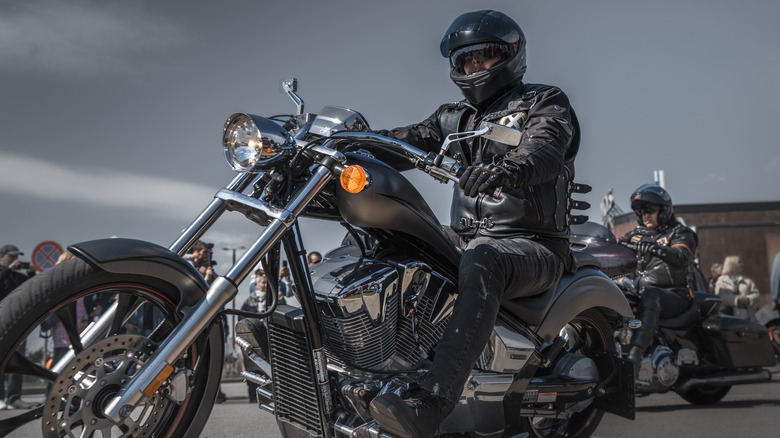 A man riding a motorcycle with other motorcyclists.