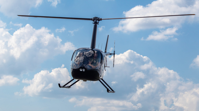 Shiny black helicopter hovering in cloudy sky