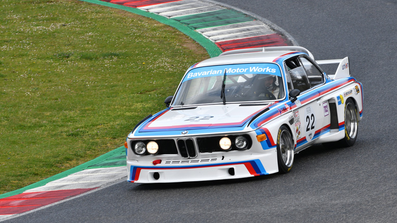 An original BMW 3.0 CSL Batmobile on a race track, front 3/4 view