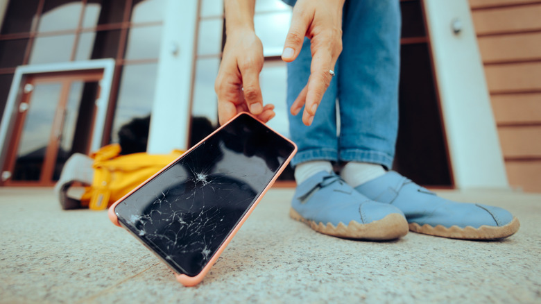 Person reaches for mobile phone dropped on the floor.