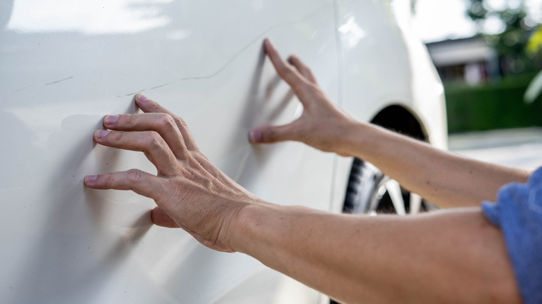 Person looking at minor damage on a car