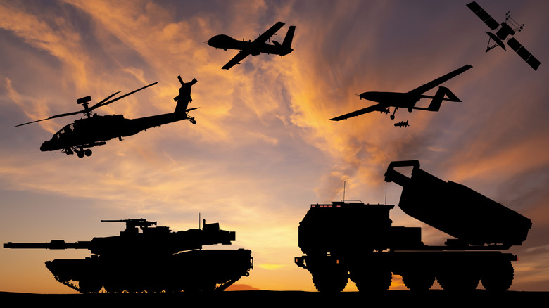 Silhouettes of variety of military vehicles at dusk