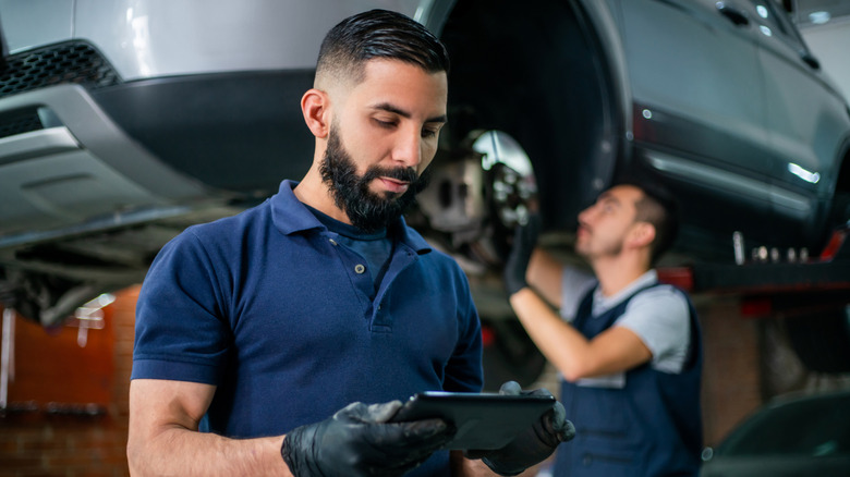 A car technician checking his tablet.