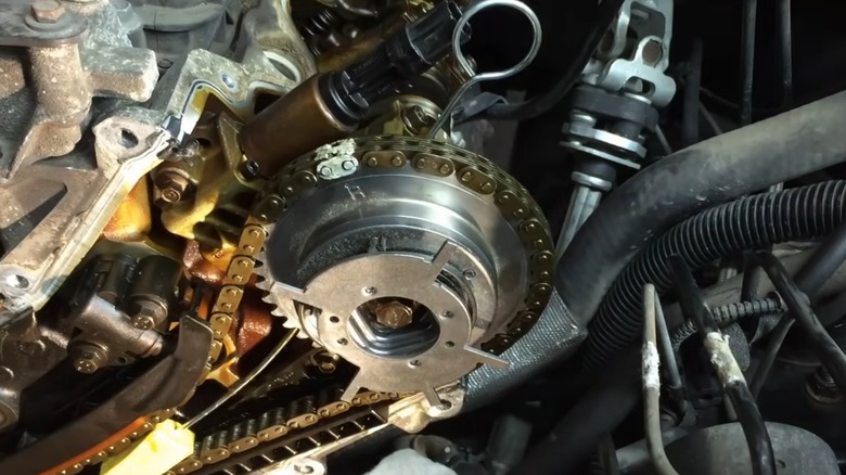 A closeup image of a camshaft phaser with timing chain in a Ford engine