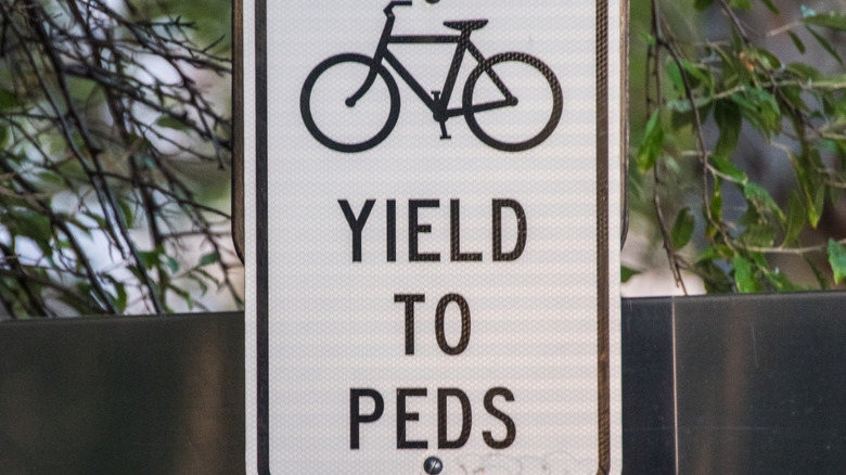 Bicycles Yield to Peds sign mounted on pole