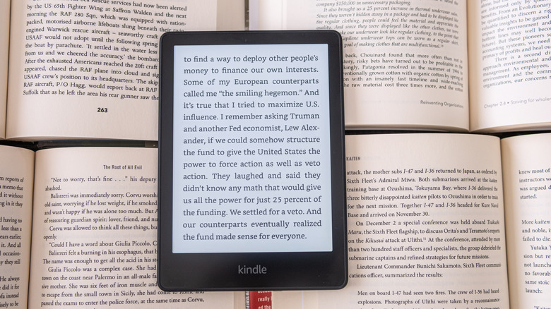 Amazon Kindle e-reader resting on top of several paper books