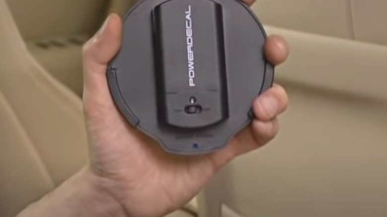 A hand holding a Power Decal inside the car before installation