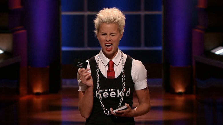 Lori holding Cheekd card on Shark Tank while winking