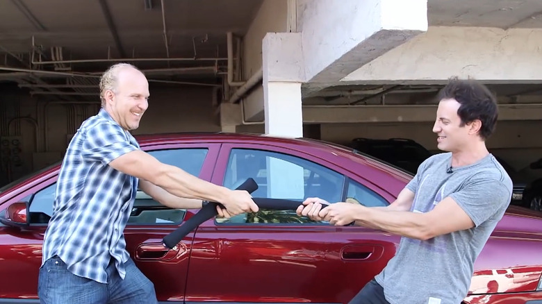 Marc and Jeff playing tug-of-war with a Drop Stop next to a red car