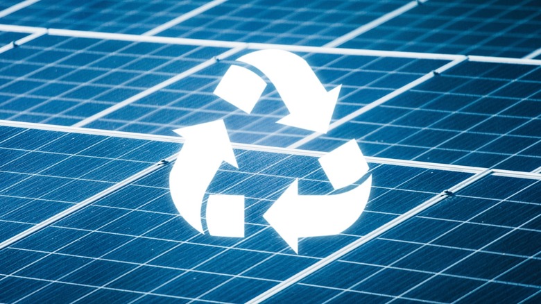 Solar panels arranged in a grid with a glowing recycle icon on top of them