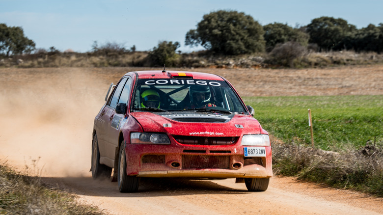 Red Mitsubishi Lancer rally car rallying on dirt