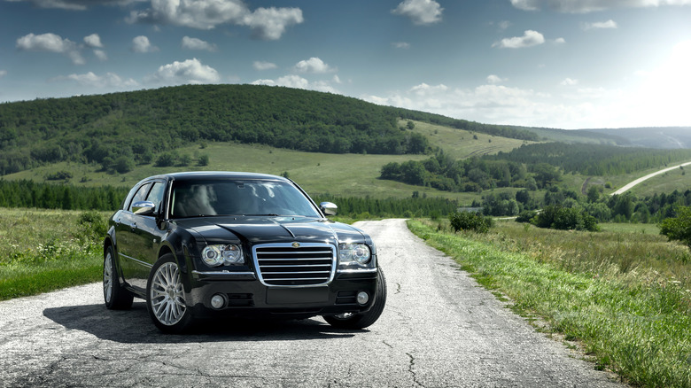 Chrysler 300C Touring on a paved road, hill in the background, front 3/4 view, black exterior