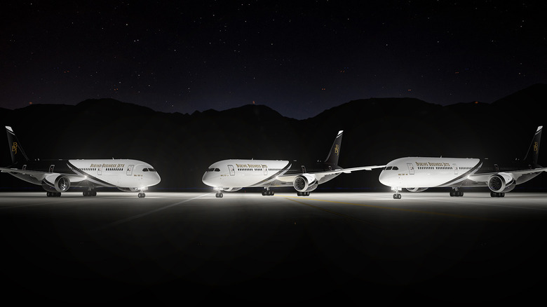 Three BBJ jets parked on a runway at night
