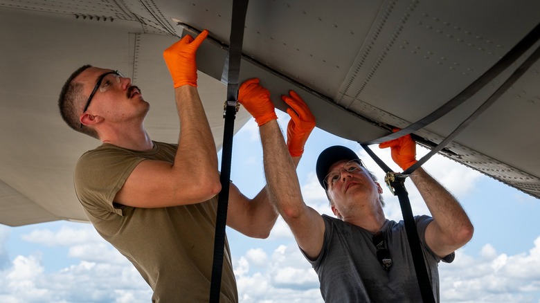 Two workers install a finlet onto an MC-130J for testing