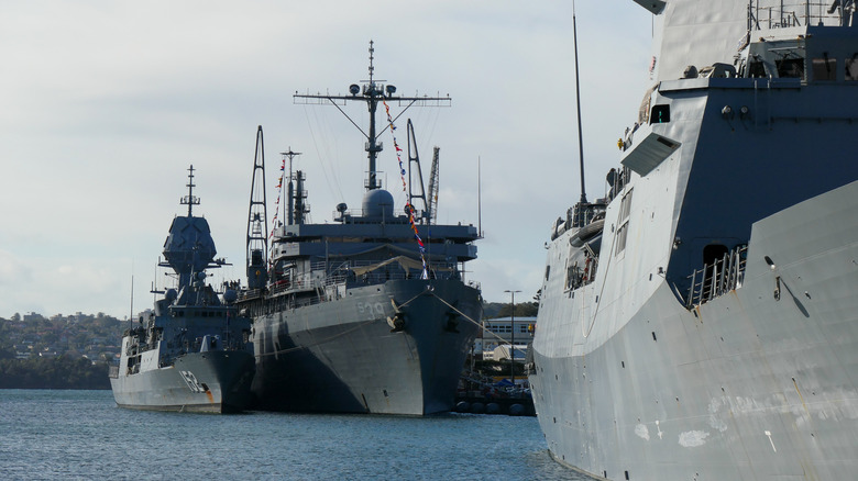 Three U.S. Navy ships docked on a cloudy day