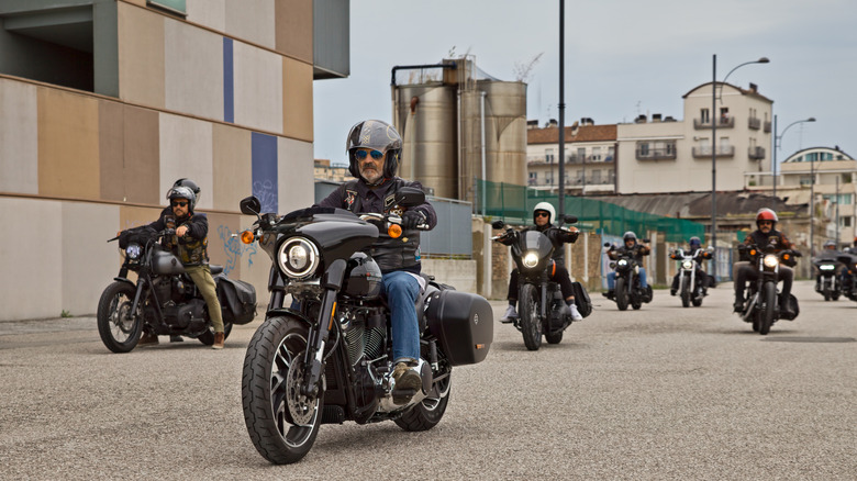 Group of bikers riding American motorbikes down a street on a sunny day
