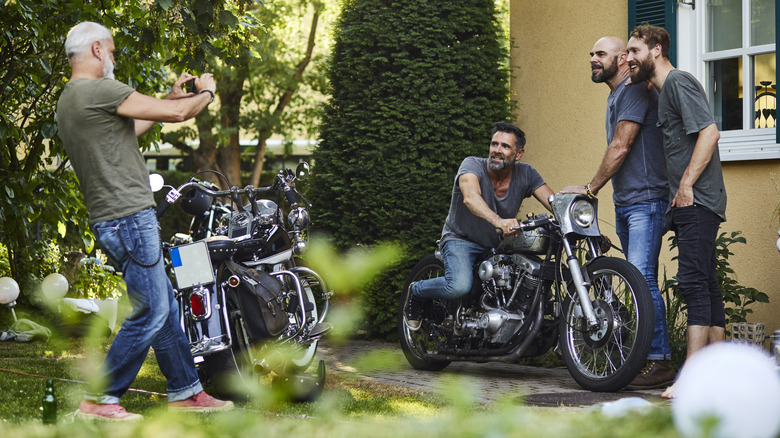 Group of middle aged men taking selfies with their motorcycles.