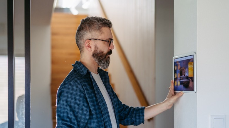 Person controlling a smart home hub mounted on a wall