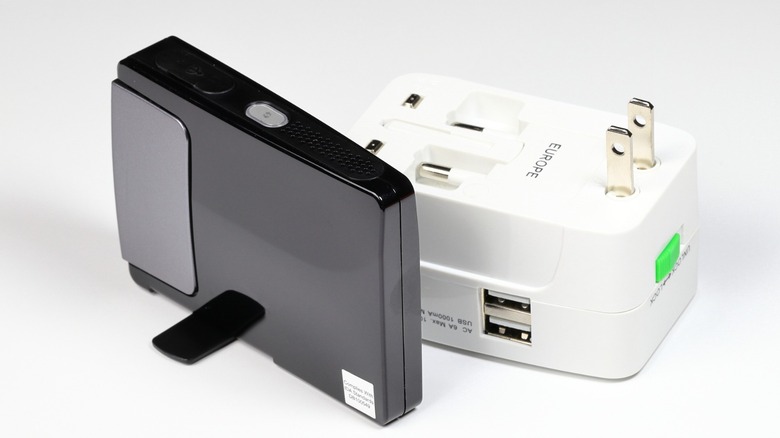 A small travel Wi-Fi router near and a travel adapter