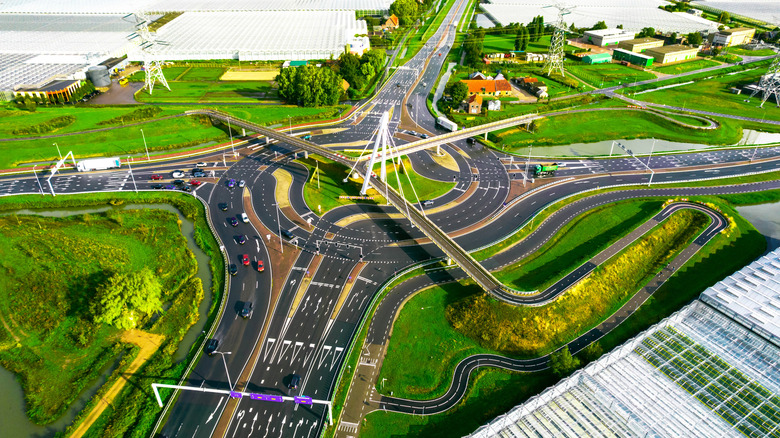An aerial shot of a complex turbo roundabout surrounded by pylons and green fields.