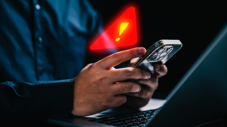 A man wearing a blue shirt using iPhone with warning sign