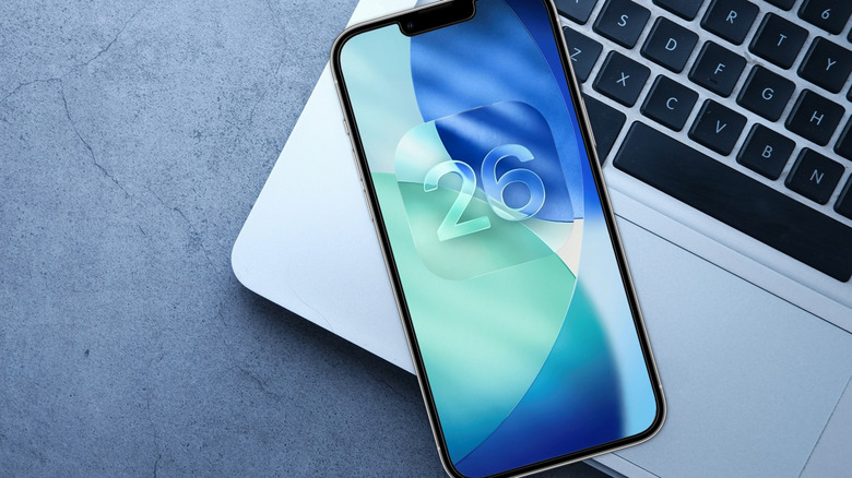 iPhone with iOS 26 logo on laptop