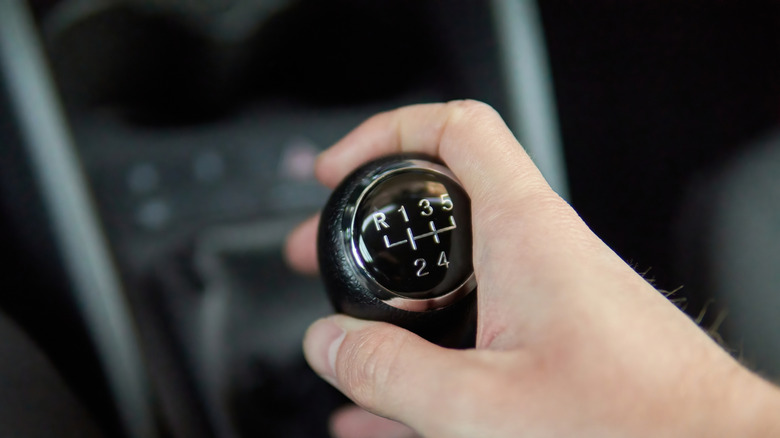 Driver's hand manipulating a car's 5-speed manual shifter