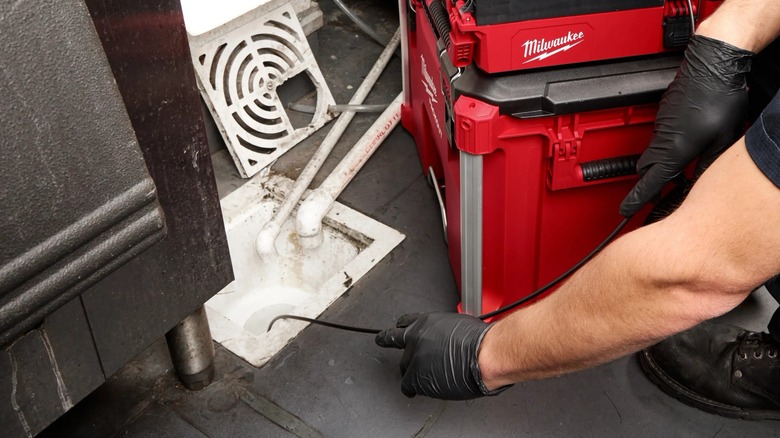 A person using a Milwaukee Packout drain camera