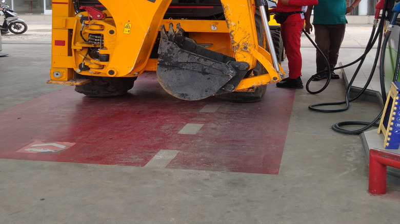 Attendants refill a JCB at a gas station