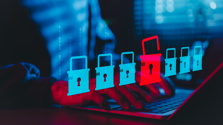 A person using laptop with digital padlock icons with a red open lock symbolizing cybersecurity threats.