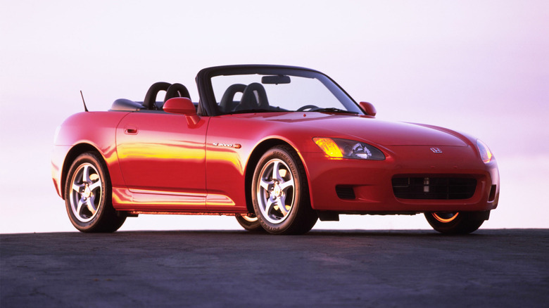 Front 3/4 view of a red AP1 Honda S2000 with the top down at sunrise