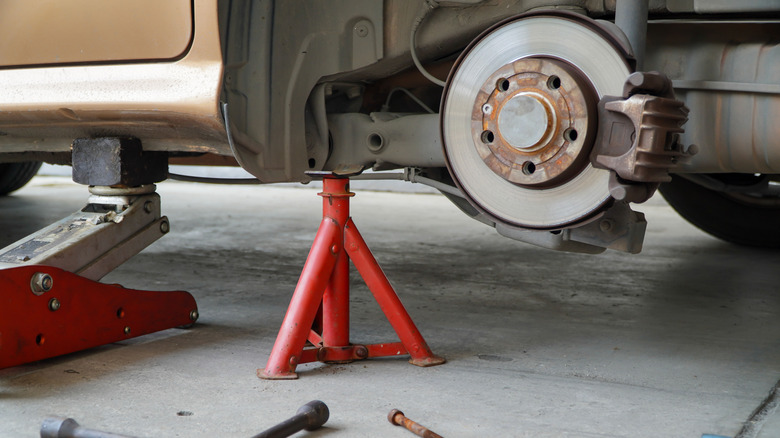 A car resting on a floor jack and jack stand