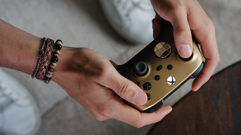 A gold Xbox One Controller being held between two hands.
